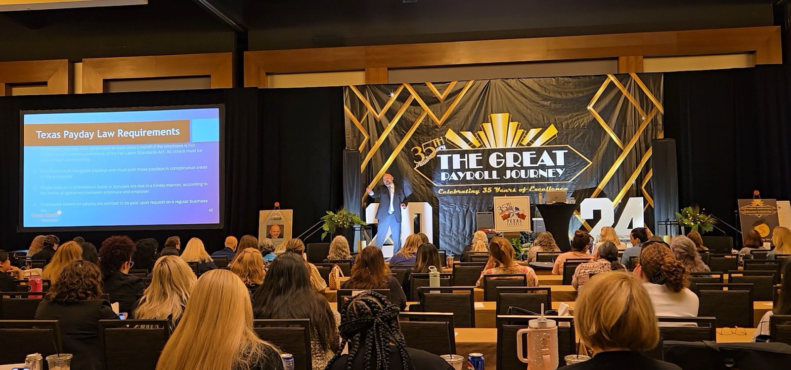 Kevin Macho on stage at the 2024 Texas Payroll Conference in a packed ballroom